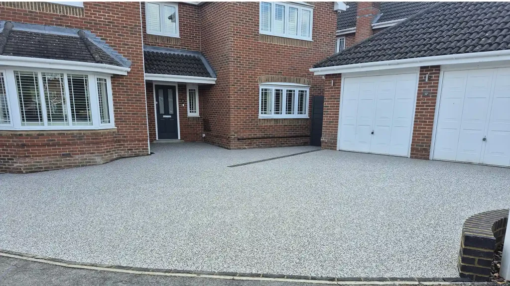 Resin bound triple car driveway with black edging and garden wall. Grey composite fencing and gate leading to the side garden.