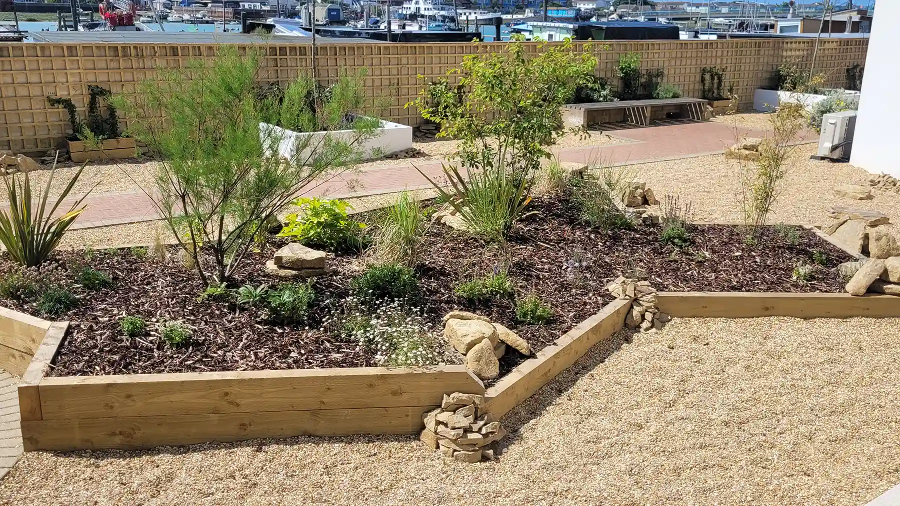 Sleeper raised bed with planting and rocks, set in a commercial apartment complex
