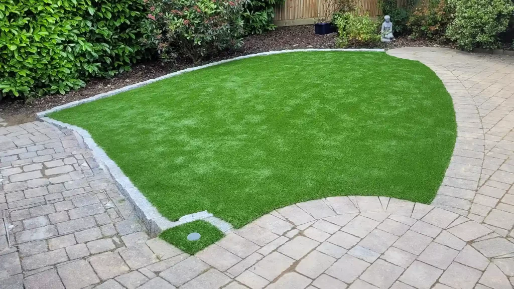 Installed artificial grass with granite sett edging.