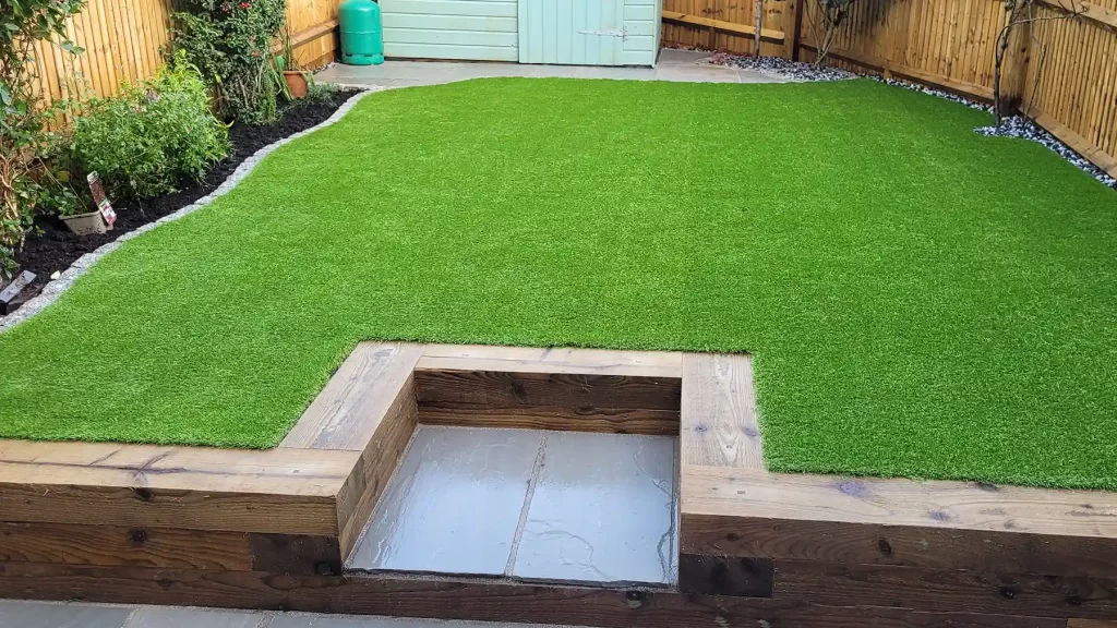 Artificial grass with sleeper steps and granite edging.