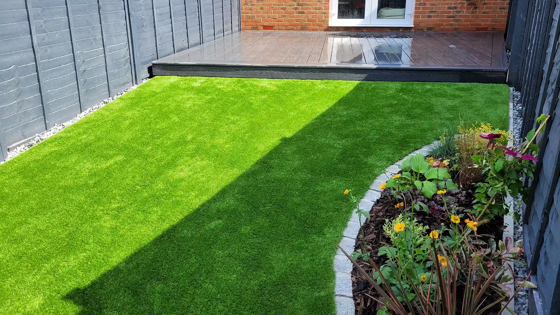 Composite decking with artificial grass and flower boarder.