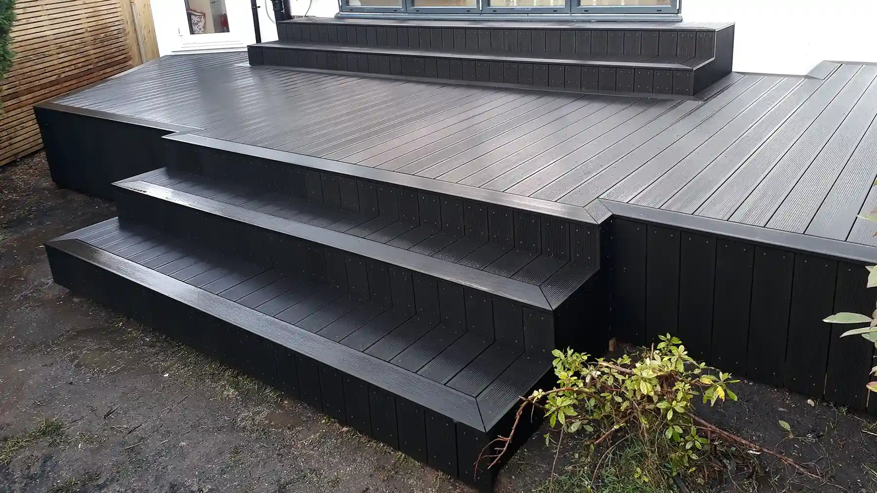 Dark grey composite decking with steps leading from bifold doors and to the garden.