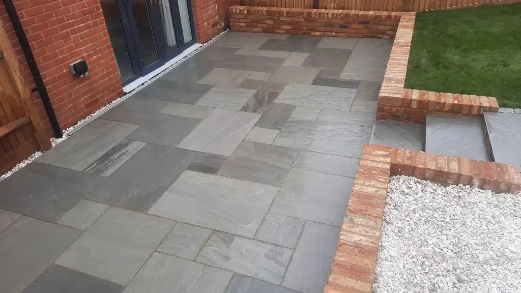 Grey sandstone patio with brick wall around the perimeter built from old farmhouse bricks.