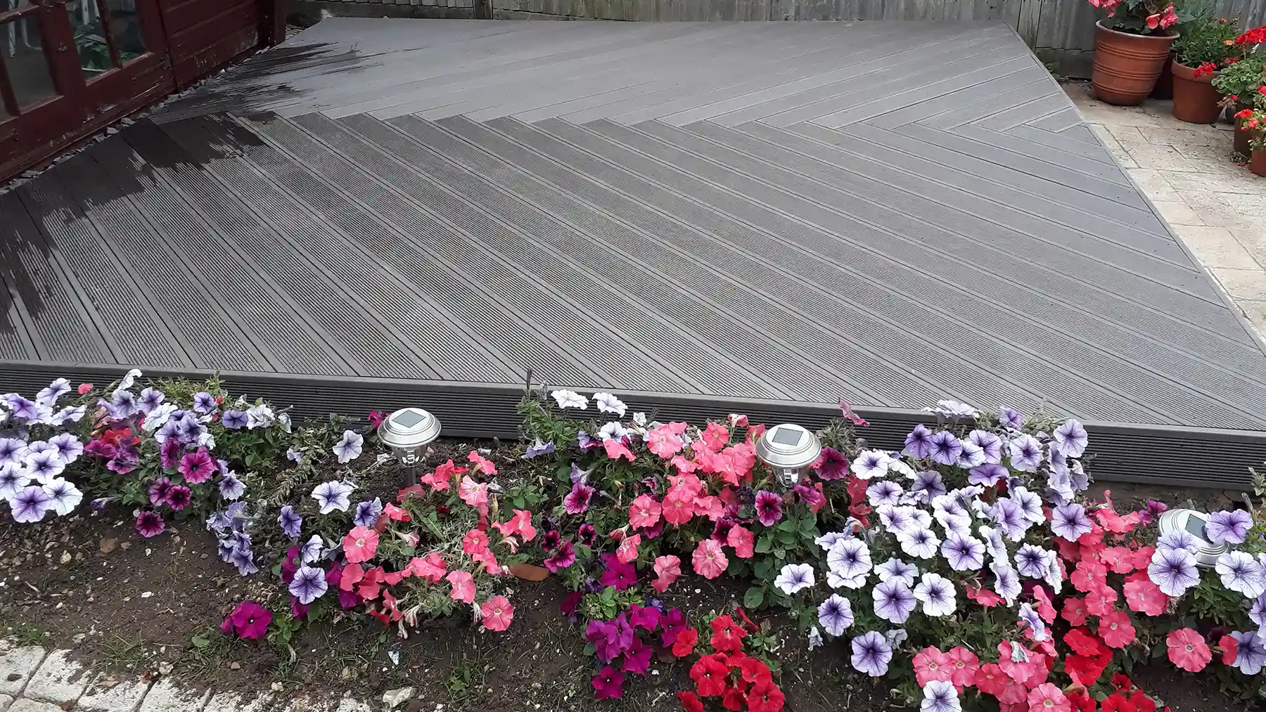 Light grey composite decking with flower bed.
