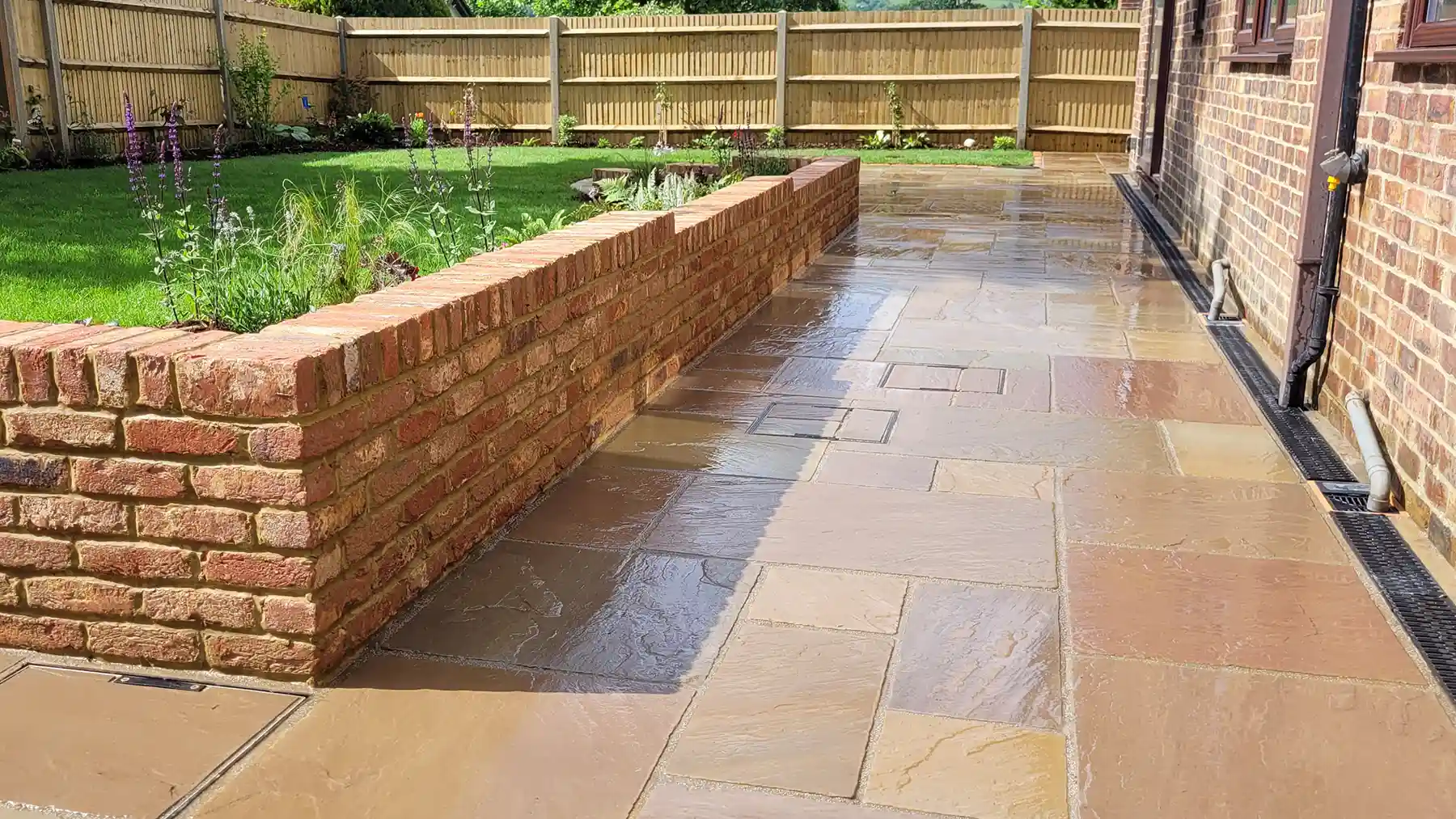 Raj green tumbled sandstone patio are with stepped brick wall.