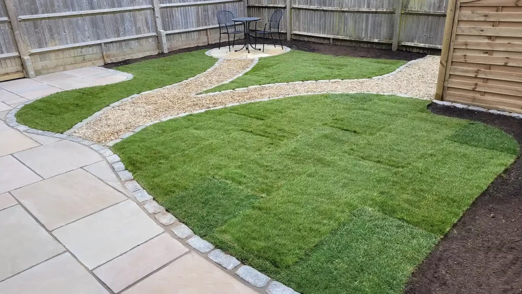 Sandstone paving with gravel pathway leading to circular patio and new lawn.