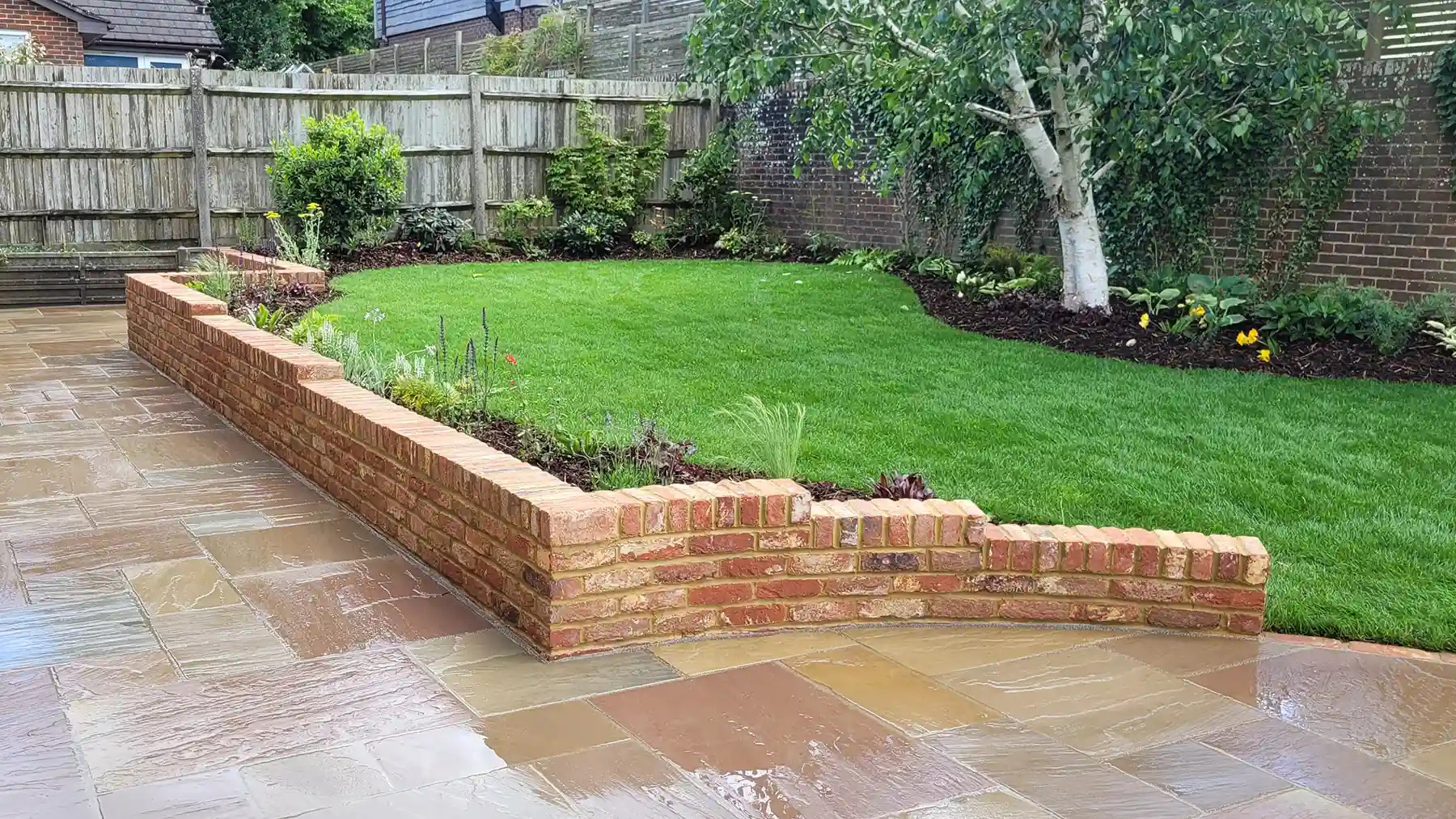 Stepped garden wall with curved ending built from old farmhouse bricks.