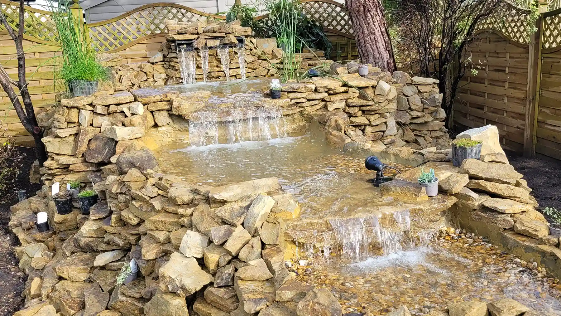 Pond-less water feature with several drops and lighting.