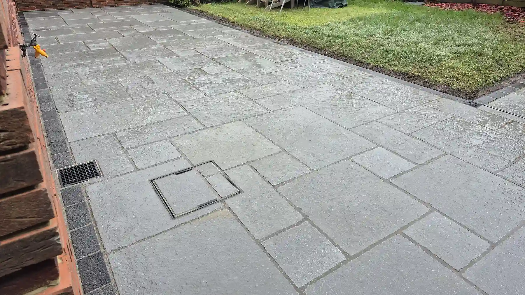 Grey limestone patio with recessed drain cover.