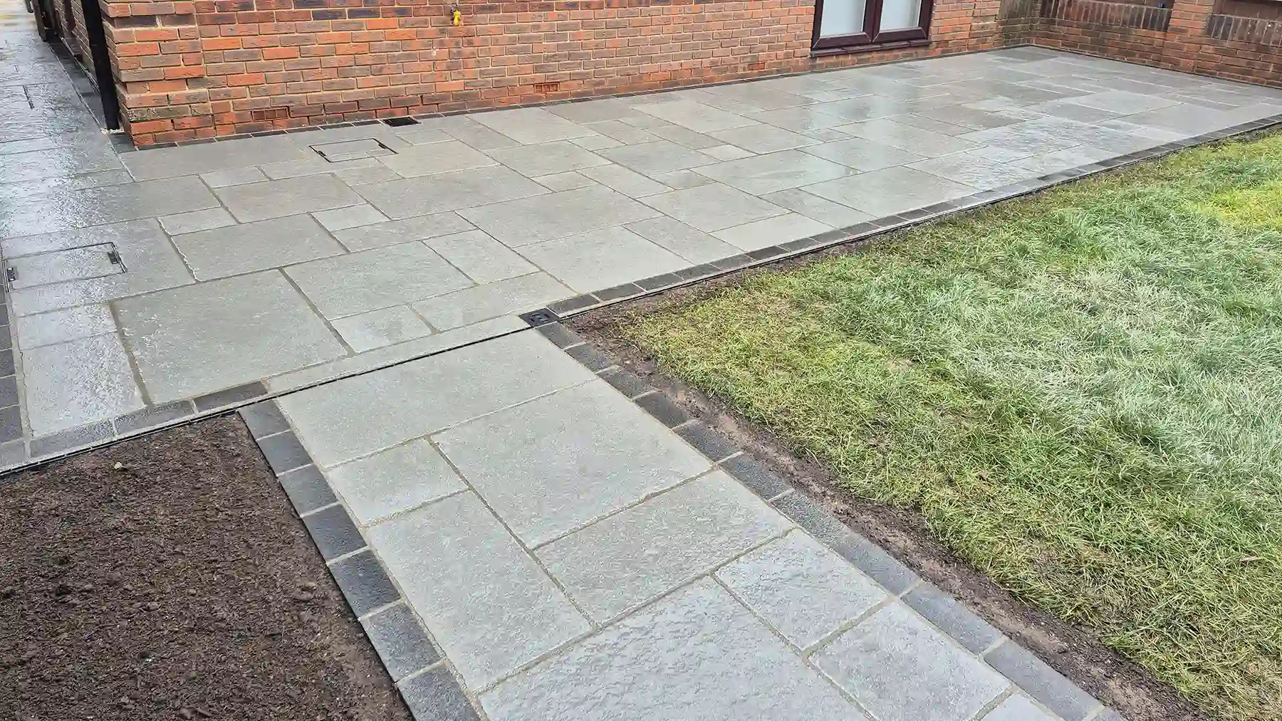 Grey limestone patio and pathway with dark granite edging, incorporating a slot drain.